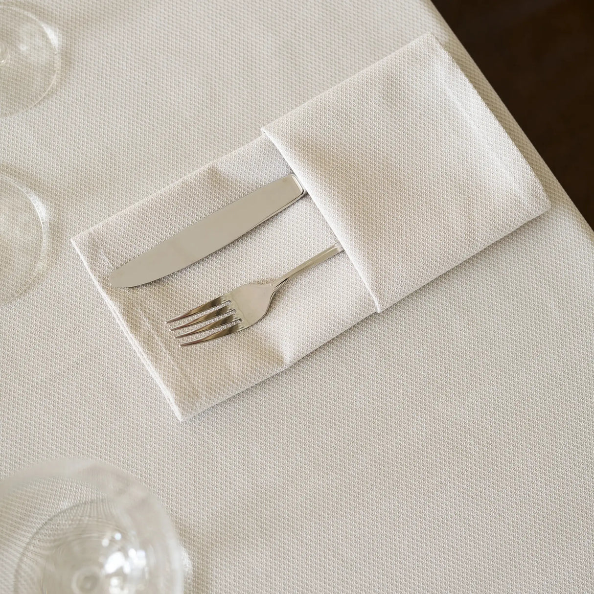 Gefaltete Bestecktasche aus beiger Serviette - stilvolle, hochwertige Tischdekoration