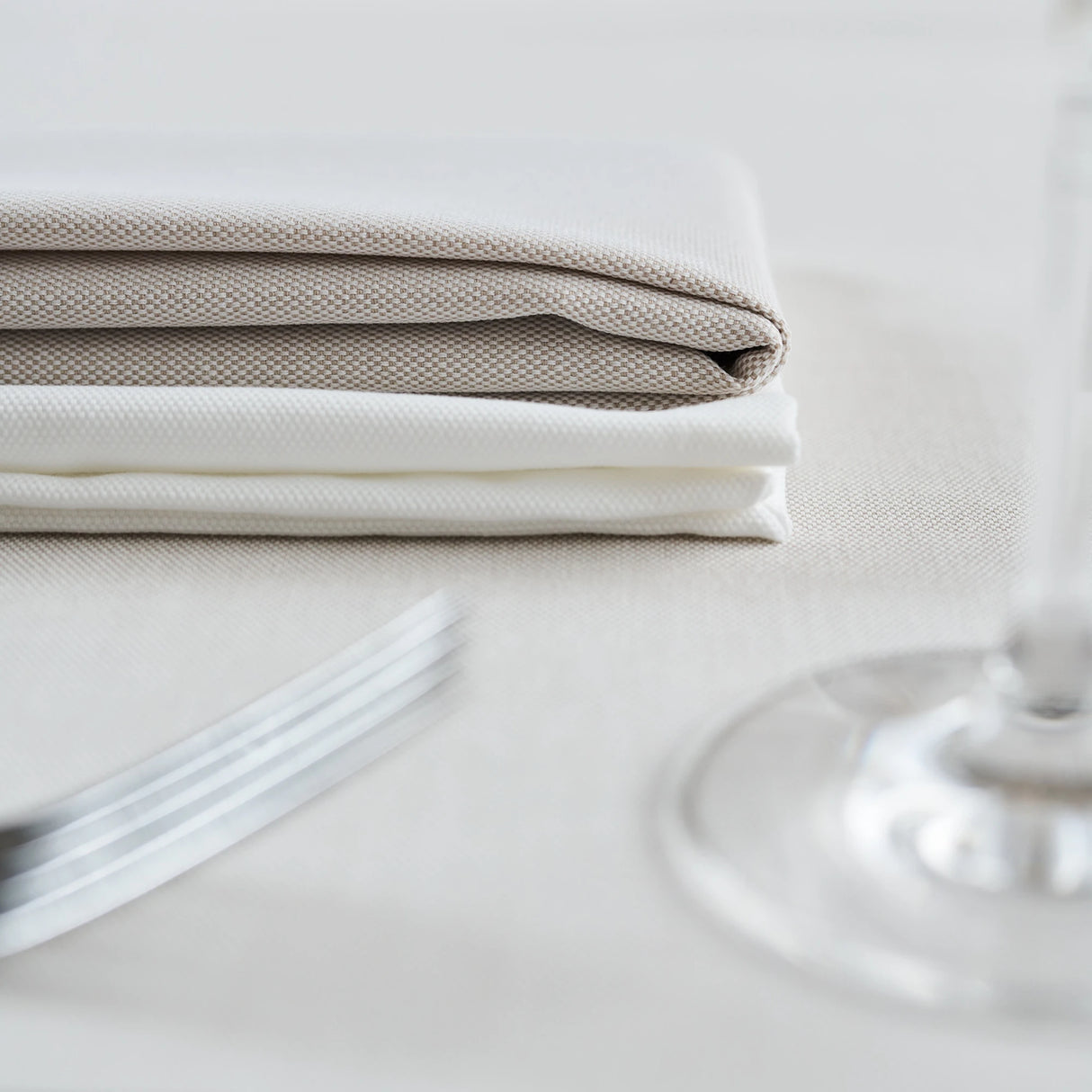 Tisch mit beige-weißer Tischwäsche & gefalteten Servietten - elegantes Restaurantdesign
