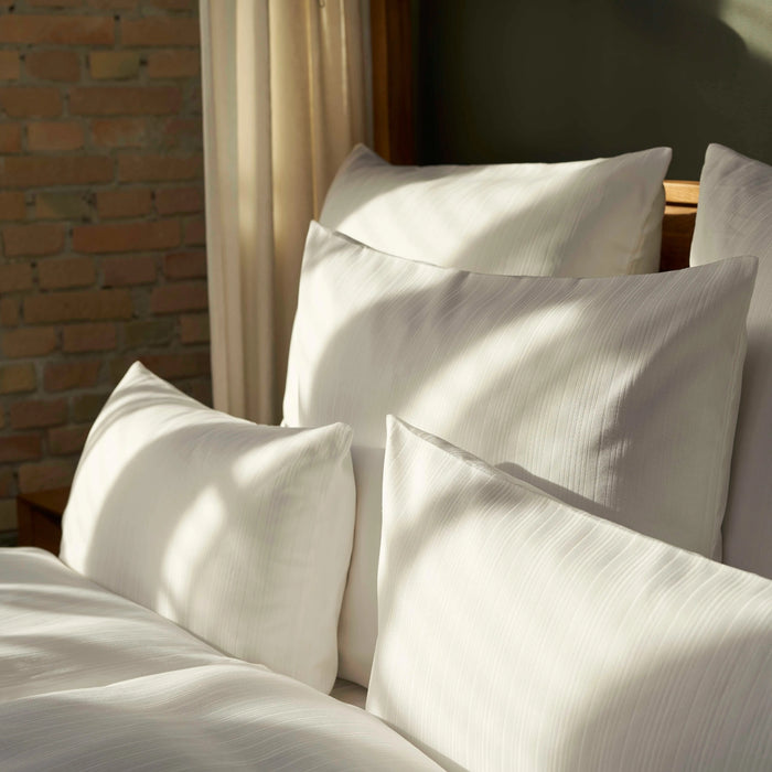 Stimmungsvolles Schlafzimmer mit Hotelbettwäsche - elegantes Design mit weichem, weißen Bettbezug