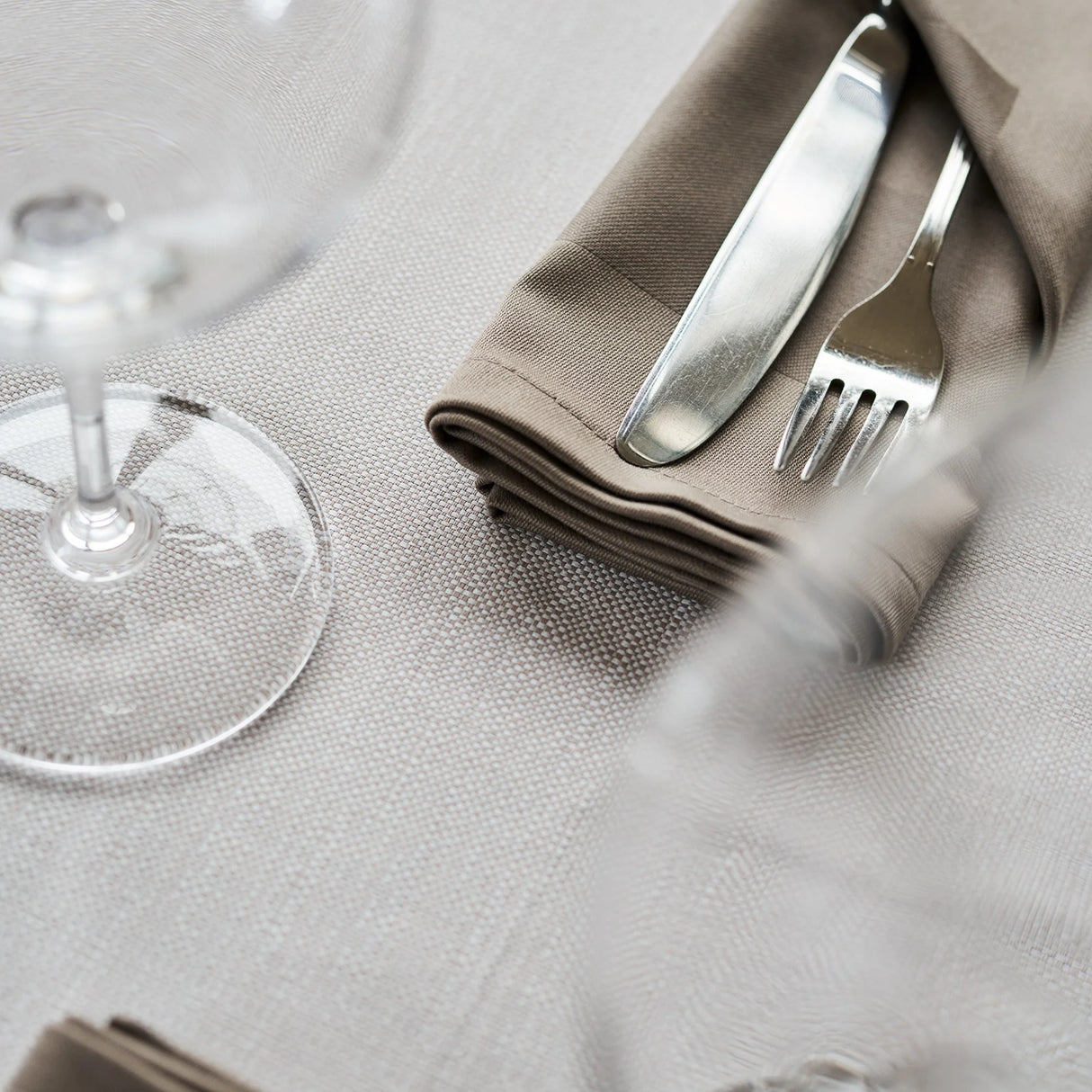 Nahaufnahme der Tischdecke Asti in Beige mit brauner Serviette - edle Farbkombination für feine Tischkultur